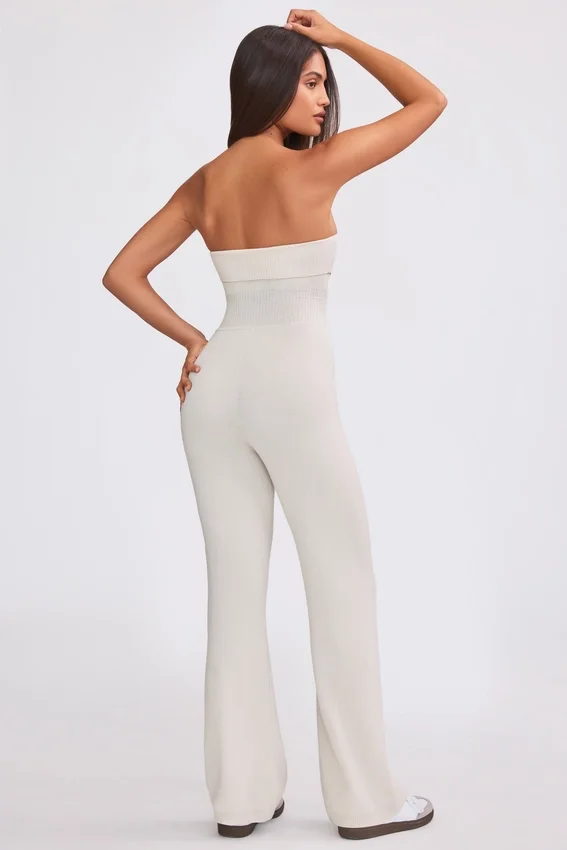 Jumpsuit i grovstickat tyg med bandeau-halsringning och utsvängda byxben i krämfärg Jumpsuit i grovstickat tyg med bandeau-halsringning och utsvängda byxben i krämfärg