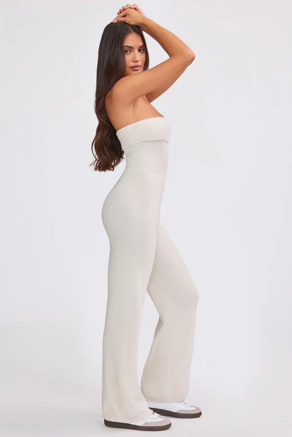 Jumpsuit i grovstickat tyg med bandeau-halsringning och utsvängda byxben i krämfärg Jumpsuit i grovstickat tyg med bandeau-halsringning och utsvängda byxben i krämfärg
