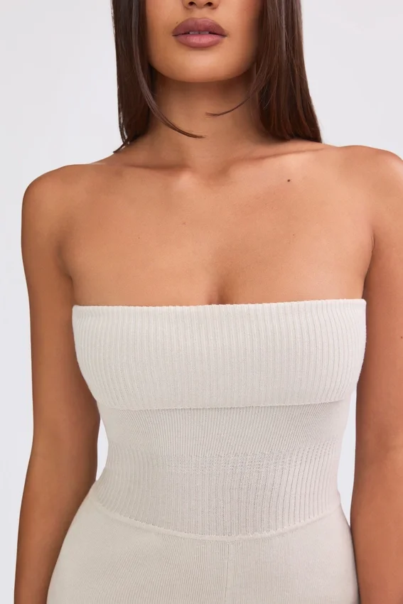 Jumpsuit i grovstickat tyg med bandeau-halsringning och utsvängda byxben i krämfärg Jumpsuit i grovstickat tyg med bandeau-halsringning och utsvängda byxben i krämfärg
