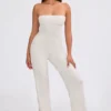 Jumpsuit i grovstickat tyg med bandeau-halsringning och utsvängda byxben i krämfärg Jumpsuit i grovstickat tyg med bandeau-halsringning och utsvängda byxben i krämfärg