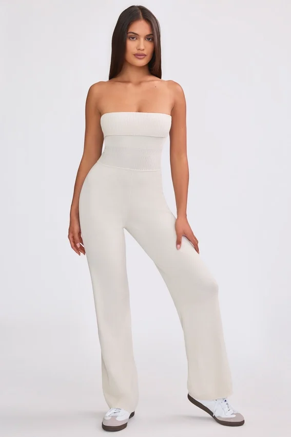 Jumpsuit i grovstickat tyg med bandeau-halsringning och utsvängda byxben i krämfärg Jumpsuit i grovstickat tyg med bandeau-halsringning och utsvängda byxben i krämfärg