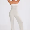 Jumpsuit i grovstickat tyg med bandeau-halsringning och utsvängda byxben i krämfärg Jumpsuit i grovstickat tyg med bandeau-halsringning och utsvängda byxben i krämfärg