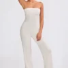 Jumpsuit i grovstickat tyg med bandeau-halsringning och utsvängda byxben i krämfärg Jumpsuit i grovstickat tyg med bandeau-halsringning och utsvängda byxben i krämfärg