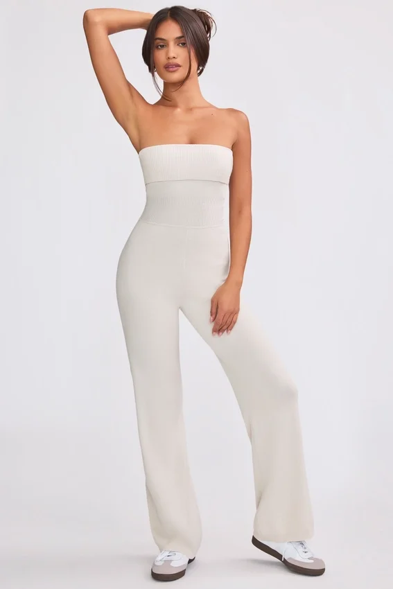 Jumpsuit i grovstickat tyg med bandeau-halsringning och utsvängda byxben i krämfärg Jumpsuit i grovstickat tyg med bandeau-halsringning och utsvängda byxben i krämfärg