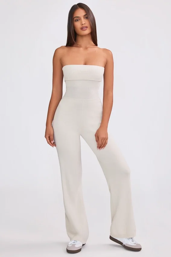 Jumpsuit i grovstickat tyg med bandeau-halsringning och utsvängda byxben i krämfärg Jumpsuit i grovstickat tyg med bandeau-halsringning och utsvängda byxben i krämfärg