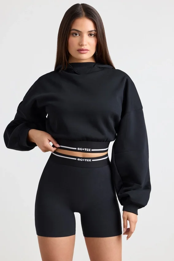 Kort hoodie i stretchig bomullsfleece i svart Kort hoodie i stretchig bomullsfleece i svart
