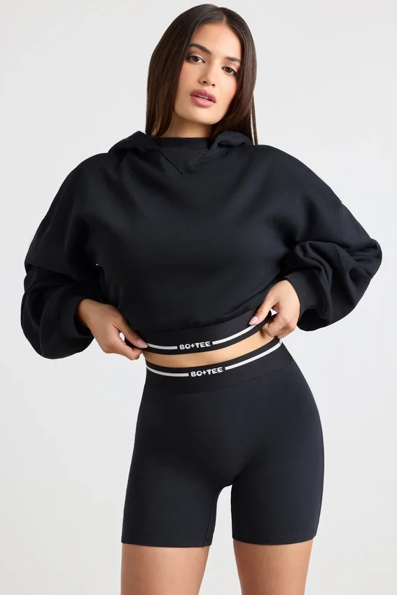 Kort hoodie i stretchig bomullsfleece i svart Kort hoodie i stretchig bomullsfleece i svart