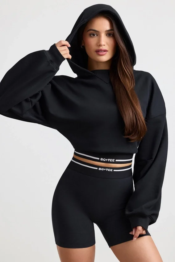 Kort hoodie i stretchig bomullsfleece i svart Kort hoodie i stretchig bomullsfleece i svart