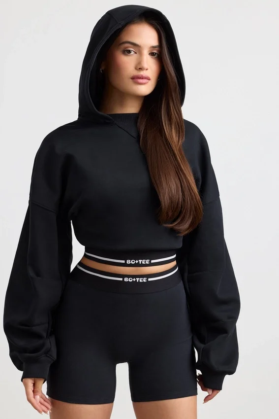 Kort hoodie i stretchig bomullsfleece i svart Kort hoodie i stretchig bomullsfleece i svart