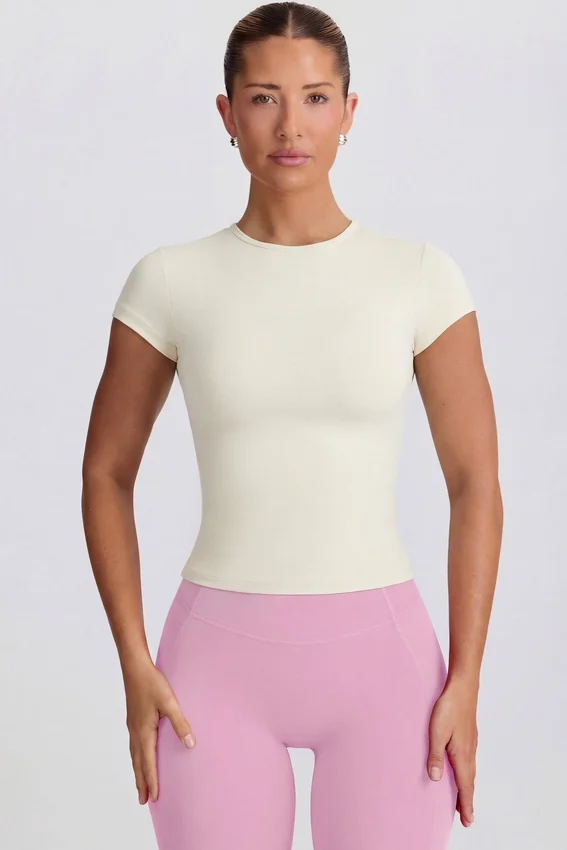 Lång T-shirt med utskärningar i krämfärg Lång T-shirt med utskärningar i krämfärg
