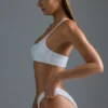 Oh Polly Badkläder: HOTFIX Edition Bandeau-bikinitopp med en axel och dekorationer i vitt Oh Polly Badkläder: HOTFIX Edition Bandeau-bikinitopp med en axel och dekorationer i vitt